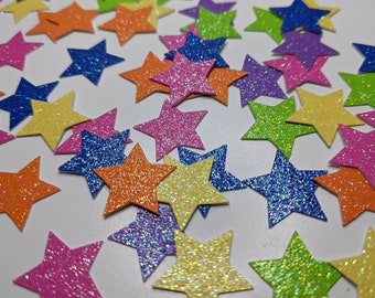 May include: A collection of colorful glitter star-shaped confetti. The stars are in various shades of pink, blue, green, yellow, and orange.
