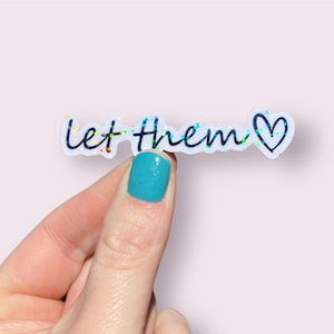 May include: A white sticker with iridescent glitter and the text "Let them" followed by a black heart.