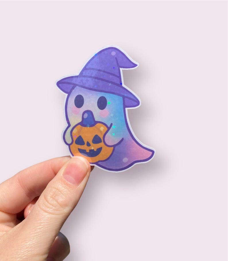 May include: A whimsical Halloween sticker featuring a cute ghost wearing a purple witch hat and holding an orange jack-o'-lantern. The ghost has a colorful, pastel body with glitter accents. A fun, festive design for Halloween.