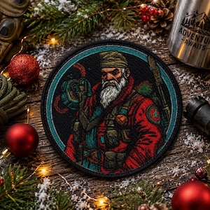 May include: A circular embroidered patch featuring a bearded person wearing a beanie and a red jacket, holding a tool. The patch has a dark teal border and is set against a festive background with pine branches, red ornaments, and a metal mug.