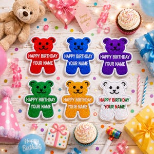 May include: Six embroidered bear-shaped patches in red, blue, purple, green, orange, and white. Each patch features the text 'HAPPY BIRTHDAY' and 'YOUR NAME' in black lettering. The patches are arranged on a surface with party decorations.