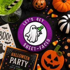 May include: A circular embroidered patch with a purple border and white center featuring a white ghost holding a green margarita glass. The text LET'S GET SHEET-FACED is stitched in white around the border. The patch is surrounded by Halloween decor.