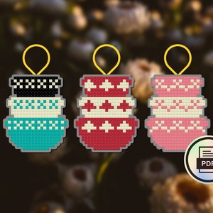 May include: Three stackable bowl ornaments with different patterns. The top bowl is black and white checkered, the middle bowl is white with black accents, and the bottom bowl is teal with white accents. The ornaments are hanging from gold loops.