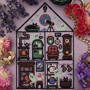 May include: A cross-stitch pattern of a haunted house with a black cat, ghosts, and other spooky details. The house is divided into five rooms, each with its own unique decor. The pattern is stitched on a purple fabric and includes the text "@stitchsprout".