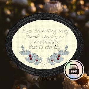 May include: A black framed embroidery hoop with white fabric and blue and red embroidery of a quote: "from my rotting body flowers shall grow i am in them that is eternity".