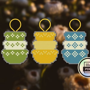 Könnte beinhalten: Drei stapelbare Schalenornamente in Grün, Gelb und Blau mit weißen geometrischen Mustern. Jedes Ornament hat eine gelbe Schlaufe zum Aufhängen.