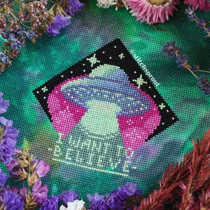 K&ouml;nnte beinhalten: Kreuzstichmuster eines UFOs mit Sternen und dem Text "I have to believe" auf einem gr&uuml;n-violetten Tie-Dye-Hintergrund.