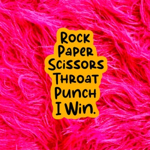 May include: A yellow sign with the text "Rock Paper Scissors Throat Punch I Win." on a pink fuzzy background.