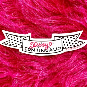 May include: White sticker with black polka dots and the text "Pray Continually 1 Thess 5:17" on a pink fuzzy background.