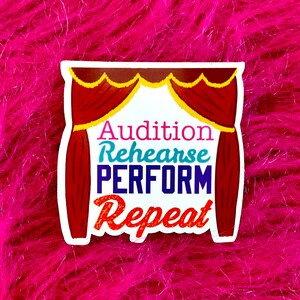 May include: A white sticker with a red and gold stage curtain design. The text on the sticker reads "Audition Rehearse PERFORM Repeat".