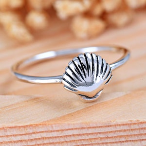 May include: A silver ring with a seashell design. The ring is simple and delicate, perfect for everyday wear.