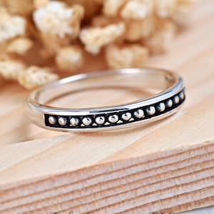 May include: A silver band ring with a row of small silver beads around the center.