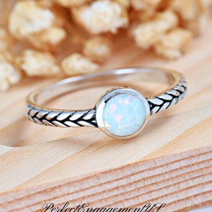 May include: A silver ring with a braided band and a white opal gemstone.