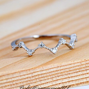 May include: A silver ring with a wavy design and small clear stones.