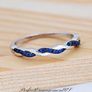 May include: A silver band ring with a twisted design and blue gemstones.