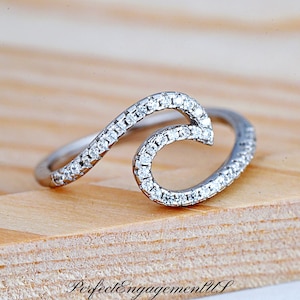 May include: A silver wave ring with a row of small clear cubic zirconia stones around the band and the wave.