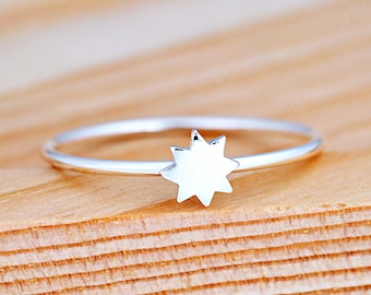 May include: A silver ring with a star-shaped design. The ring is thin and delicate, and the star is simple and modern.