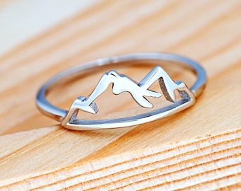 Op de afbeelding: Een zilveren ring met een bergketenontwerp. De ring is eenvoudig en elegant en zou een geweldig cadeau zijn voor iedereen die van de buitenlucht houdt.