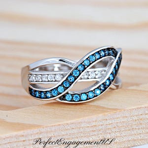May include: A silver ring with a blue and white infinity design. The ring is set with small blue and white gemstones.