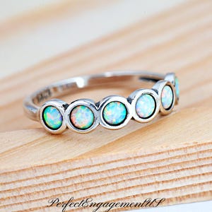 May include: A silver ring with six round opal stones set in a curved band.
