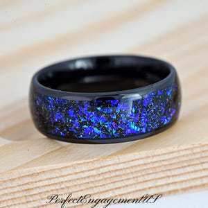 May include: A black tungsten carbide ring with a blue glitter inlay. The ring is polished and has a smooth finish.