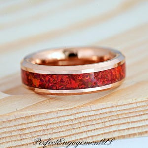 May include: A rose gold tungsten carbide ring with a red and brown inlay. The ring has a beveled edge and a polished finish.