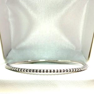 Op de afbeelding: Een zilveren armband met een geperlde rand.