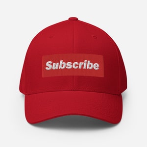 May include: Red baseball cap with a white embroidered "Subscribe" patch on the front.