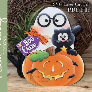 May include: A laser-cut wooden sign featuring a white ghost wearing black glasses, a black cat, and an orange jack-o'-lantern. A purple tag reads "Boo Crew" with an orange polka-dot bow. Text at the top reads "SVG Laser Cut File PDF File".