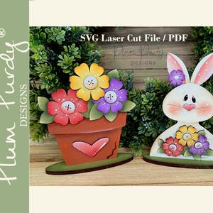 Puede incluir: Decoraciones de Pascua de madera. Un macetero con flores rojas, amarillas y moradas y un conejito con orejas rosas. El macetero tiene un corazón. El texto "SVG Laser Cut File / PDF" es visible.