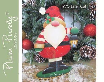 May include: A red and white striped Santa Claus holding a lantern with a candle inside. The Santa Claus is standing on a green base with a yellow border. The background is a green Christmas tree with red and gold ornaments.