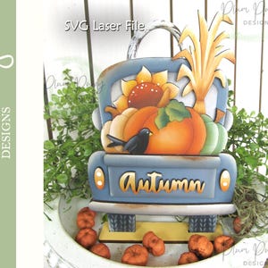 May include: A wooden, blue truck-shaped decoration with the word "Autumn" on the tailgate. The truck bed is filled with pumpkins, a sunflower, and corn stalks. A small black bird sits on the front of the truck. The words "SVG Laser File" are at the top.