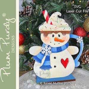 May include: A whimsical snowman-shaped decoration, crafted from wood, features a blue scarf, a red heart, and a carrot nose. The snowman's head is topped with a whipped cream design and a candy cane. The text "SVG Laser Cut File" is visible.