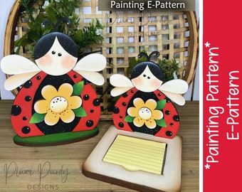 May include: Two wooden ladybug note holders painted in red, black, white, and yellow with a yellow flower and green leaves. The larger ladybug is a stand-alone piece, while the smaller ladybug is attached to a wooden base with a yellow notepad.