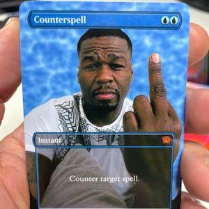 May include: A rectangular trading card with a blue water-patterned border. The card features the text Counterspell at the top, two blue mana symbols, and an image of a man holding up a middle finger. The text box reads Instant and Counter target spell.