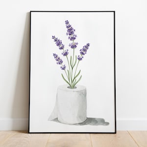 May include: A framed watercolor print featuring a roll of white toilet paper with lavender sprigs emerging from the center. The lavender has purple flowers and green stems and leaves. The print is set against a white background.