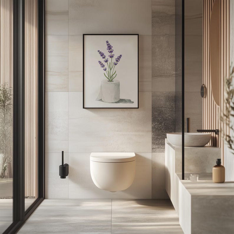May include: A modern bathroom featuring a wall-mounted toilet, a framed watercolor print of lavender in a toilet paper roll, and a minimalist sink area. The color palette is neutral with shades of white, gray, and beige, creating a serene atmosphere.