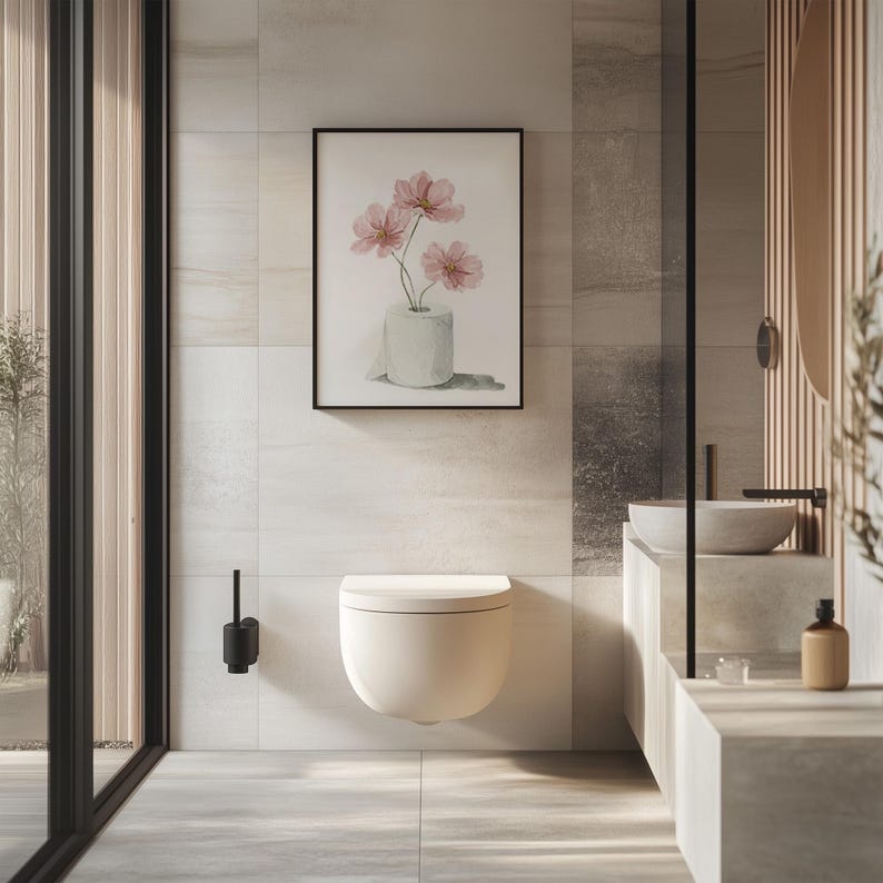Puede incluir: Un ba&ntilde;o moderno con inodoro suspendido y una impresi&oacute;n enmarcada en acuarela de flores rosas en un rollo de papel higi&eacute;nico. La habitaci&oacute;n tiene baldosas de color claro y una mampara de ducha de cristal, creando una est&eacute;tica minimalista.