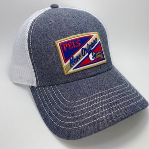 May include: A blue and white trucker hat with a gold, red, blue, and white patch that says "PELS New Orleans" with a pelican logo.