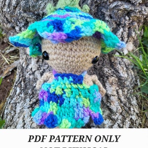 May include: Crochet pattern for a whimsical, colorful fairy doll with a blue, green, and purple hat. The doll is wearing a blue, green, and purple dress. PDF pattern only, not a physical product.