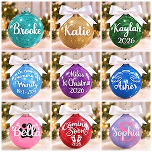 May include: A collection of nine round, glittery Christmas baubles in various colours, each topped with a white satin bow. The baubles feature personalised white text, including names like Brooke, Katie, Kaylah, Wendy, Mila, Asher, Bella, and Sophia, plus dates and graphics.