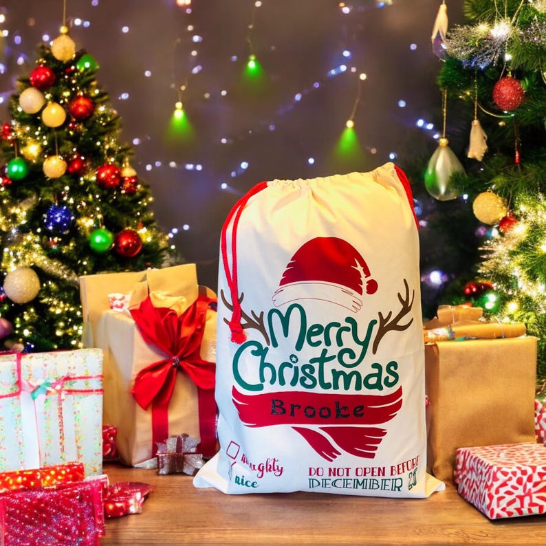 May include: A white canvas Santa sack with red drawstring and a green and red "Merry Christmas" graphic. The sack is personalized with the name "Brooke" and has a "Naughty or Nice" checkbox and the text "Do Not Open Before December 24th".
