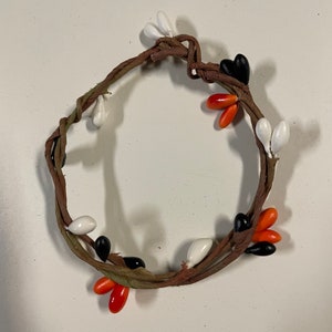 May include: A brown twig wreath decorated with white, orange, and black berry-shaped ornaments.