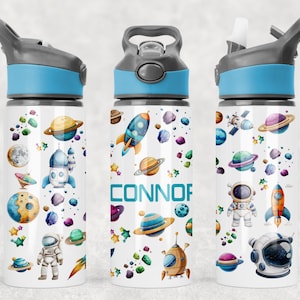 May include: A white water bottle with a blue and grey lid, decorated with a space theme. The design includes planets, rockets, astronauts, and the name "CONNOR". The bottle is designed for children.
