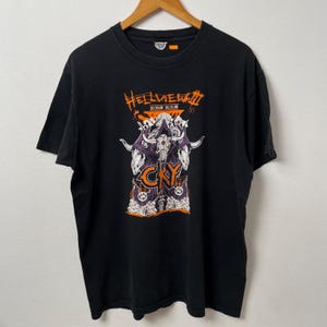 May include: Black t-shirt with a graphic design featuring a skull, horns, and the text "Hellview III" in orange. The design also includes the text "CRY" and the dates "10.30.08 - 10.31.08". The shirt is hanging on a wooden hanger.