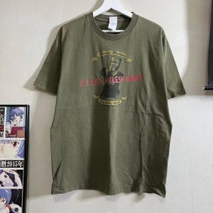 May include: A green t-shirt with a graphic print of a knight in armor with the text "Monty Python, It's Just a Flesh Wound, The Holy Grail".