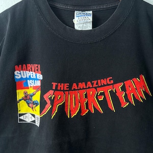 May include: A black t-shirt featuring a graphic of Spider-Man on a Marvel Super Hero Island comic book cover design. The text reads THE AMAZING SPIDER-TEAM in large red letters with yellow outlines. A Gildan Ultra Cotton size L tag is at the neck.
