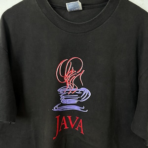 Può includere: T-shirt nero con grafica a tema caffè. Il design presenta una tazza di caffè stilizzata con accenti rossi e viola e la parola "JAVA" in corsivo rosso sotto.