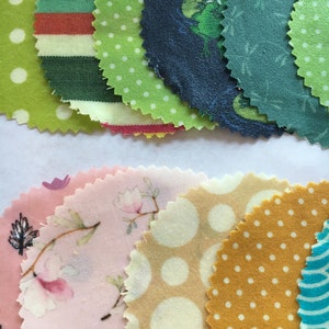May include: A collection of colorful fabric circles with scalloped edges. The fabrics feature various patterns, including polka dots, stripes, and floral designs. Colors include green, pink, yellow, and blue. These fabric circles are suitable for crafting and sewing projects.
