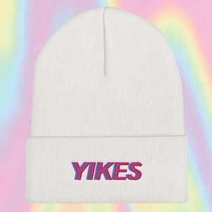 May include: White beanie with the word "YIKES" embroidered in pink and purple letters.